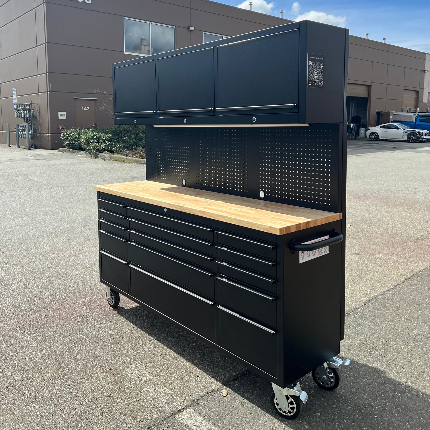 Black tool cabinet with wooden top in front of a building